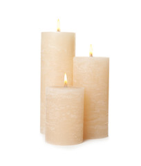 Three alight wax candles on white background