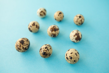 Fototapeta premium Raw quail eggs against blue background. Easter.