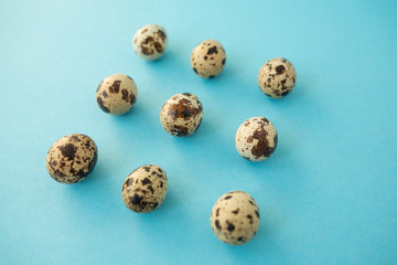 Obraz premium Raw quail eggs against blue background. Easter.