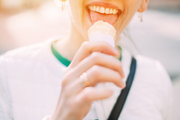Young, Caucasian, happy, smiling woman lick ice cream on background blurred sunny street.