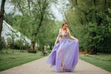 beautiful young happy girl in dress resting outdoors, woman in the park on a background of green trees