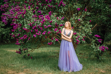 Obraz na płótnie Canvas beautiful young happy girl in an incredible dress resting outdoors,woman walking in the park amid blooming lilacs