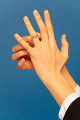 Hand putting engagement ring on wedding finger