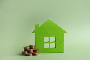 House model and coins on color background. Space for text