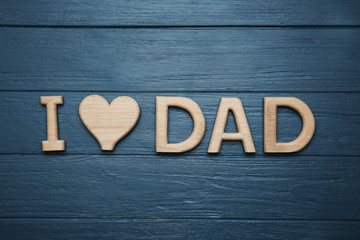 Phrase I LOVE DAD made of letters on wooden background, top view