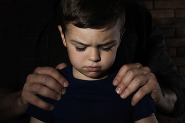 Despaired little boy and adult man on dark background. Child in danger © New Africa