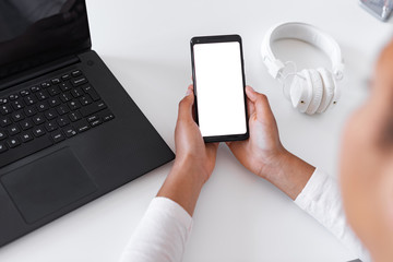 Closeup mockup image of white empty blank smartphone in the female hand