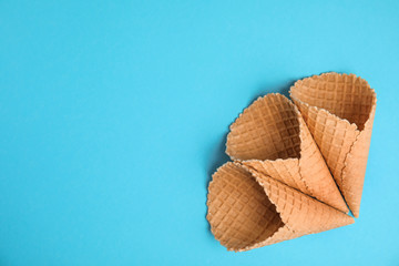 Waffle empty ice cream cones on color background, flat lay. Space for text