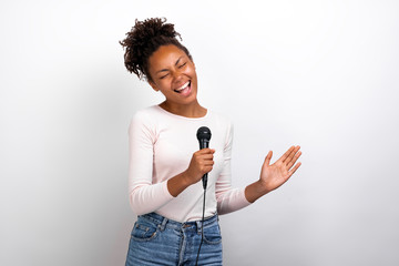 Funny woman singer holds a microphone in her hands against a ligth studio background
