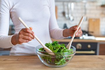 Closeup female hands during cooking a healthy food, stirs with spoons a salad