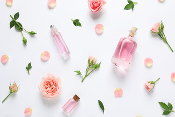 Composition with rose essential oil and flowers on white background, top view