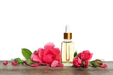 Bottle of rose essential oil and flowers on table, white background