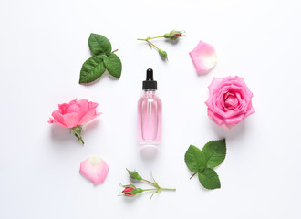 Composition with rose essential oil and flowers on white background, top view