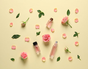 Flat lay composition with rose essential oil and flowers on color background