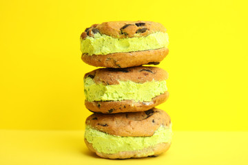 Sweet delicious ice cream cookie sandwiches on color background