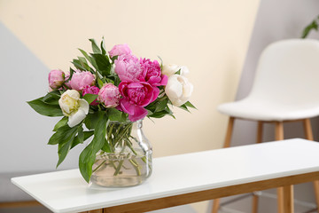 Vase with bouquet of beautiful peonies on table in room, space for text
