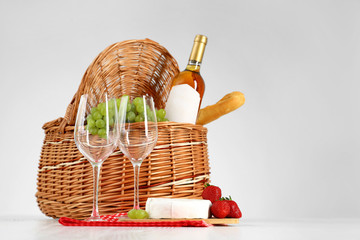 Picnic basket with wine, glasses and products on white background