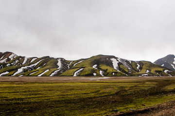 view of snowy green mountains in Landmannalaugar summer in Iceland on cloudy day