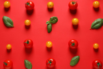 Flat lay composition with ripe cherry tomatoes and basil leaves on color background