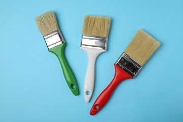 Paint brushes on color background, top view