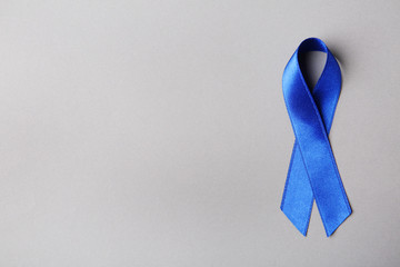 Blue ribbon on color background, top view with space for text. Colon cancer awareness concept
