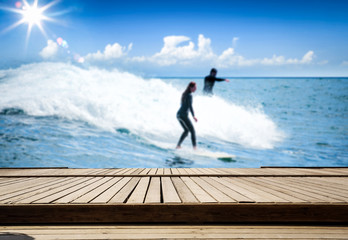 Desk of free space and summer blurred background of beach with surfers 