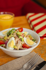 Traditional american cobb salad with chopped avocado, tomatoes, hard boiled egg, roasted chicken and greens for a healthy lunch, served with orange juice