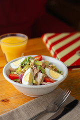 Traditional american cobb salad with chopped avocado, tomatoes, hard boiled egg, roasted chicken and greens for a healthy lunch, served with orange juice