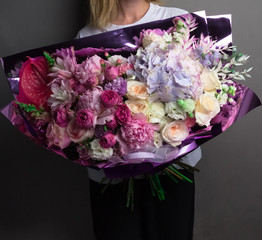 designer lush bouquet of flowers in the hands, shiny wrapping paper