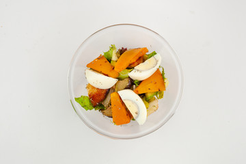 Top view of mixed green salad with persimmon and hard boiled egg, isolated on white background