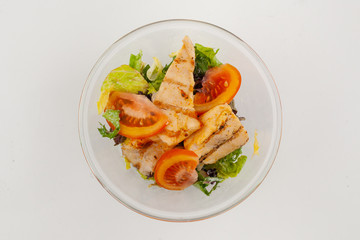 Top view of mixed green salad with grilled chicken breast, tomatoes and no dressing, isolated on white background