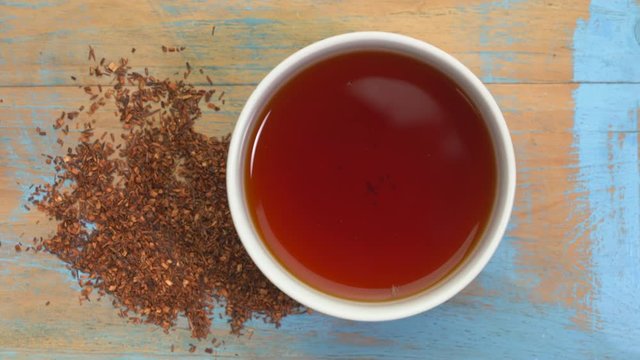 rooibos tea, made from the South African red bush, naturally caffeine free - a cup of tea and loose leaves on turntable