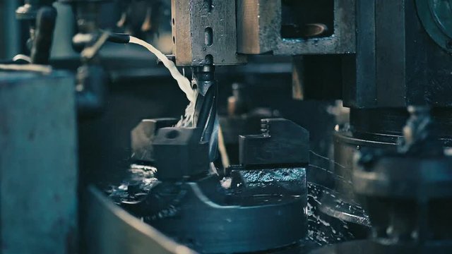 Metalworking machine. Metal detail on factory. New metal tool with oil or coolant. Fast rotation speed. Slow motion closeup