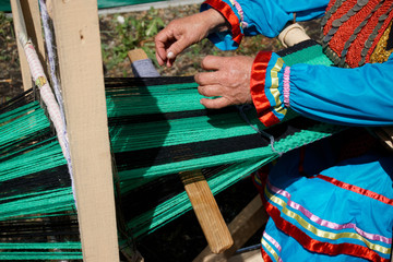 An example of the use of a handicraft loom is an elderly woman. Outdoor