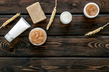 Scrabs and creams for natural cosmetic set with herbs and wheat on wooden background top view mock up