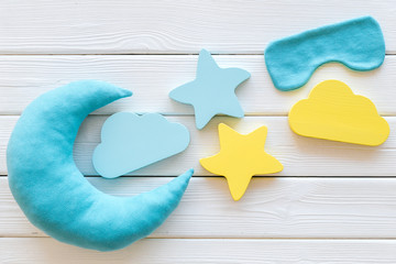 Night sleep concept with moon, stars, clouds toy and mask on white wooden background top view
