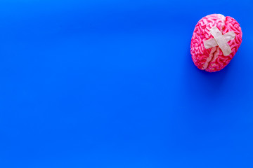 Disease of the brain concept with brain with cross-shaped patch on blue background top view