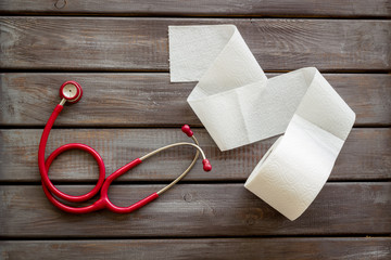 Disease of colon concept with toilet paper roll and stethoscope on wooden background top view