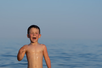 A boy of three years is swimming in the sea at sunset with his brother.