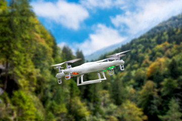 Fototapeta na wymiar White drone quadcopter flying on background of mountains. Soft focus. Motion blur.