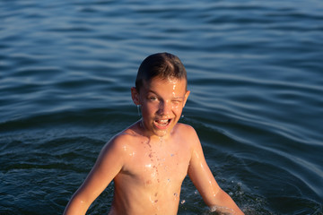 A boy of nine is swimming in the sea at sunset.