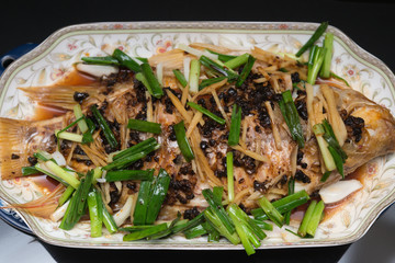 fresh steamed whole fish covered with herbs onions and sauce