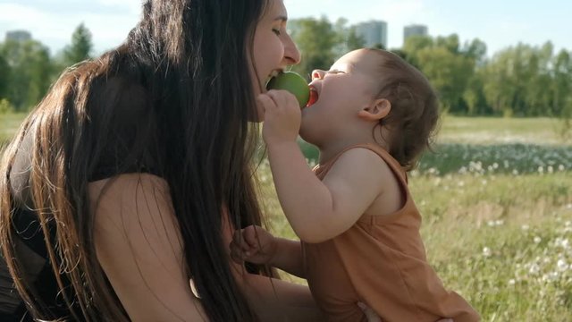 A young mother and her son eat an Apple. A small child bites an Apple.