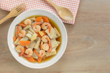 top view of stir fried king oyster mushroom with shrimp in a ceramic dish on wooden table. asian homemade style food concept.