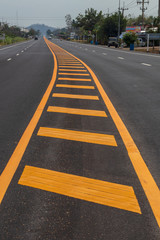 Yellow lines on the paved road with mountains.