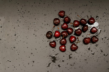 beautiful fresh sweet cherry on a black matte background with water droplets, space for text