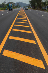 Yellow lines on the paved road with mountains.