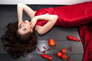Obraz na płótnie Canvas Beautiful brunette in a red silk evening dress in a chic interior.