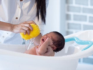 Mother bath Asian boy baby newborn on the bathtub