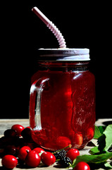 Compote of cherry and mulberry on a wooden table, sunny day.